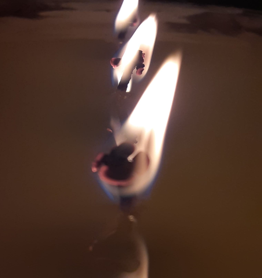 Three candle flames in a line behind each other